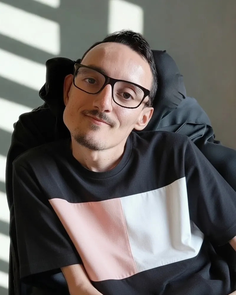 Gabriel, fundador da Marp Company, de óculos e camiseta preta, sorrindo, sentado em sua cadeira de rodas